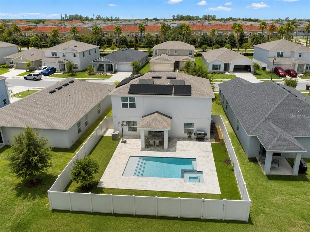 An aerial view shows a two-story house with solar panels, a backyard pool, and patio — 5225 TUSCANY LANE, DAVENPORT, FL