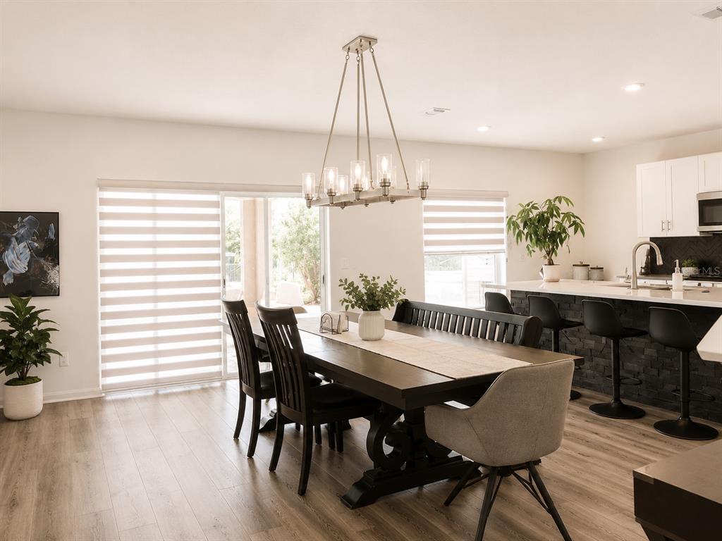 A dining area with a dark wood table, chandelier, and adjacent kitchen island with barstools — 5225 TUSCANY LANE, DAVENPORT, FL
