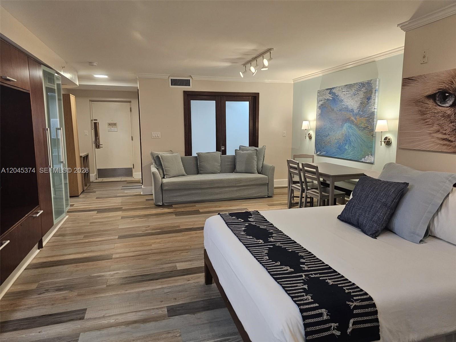 A studio apartment features a bed, a sofa, a dining set, and wood-look flooring — 1024 Ocean Dr # A305, Miami Beach FL 33139, MIAMI BEACH, FL