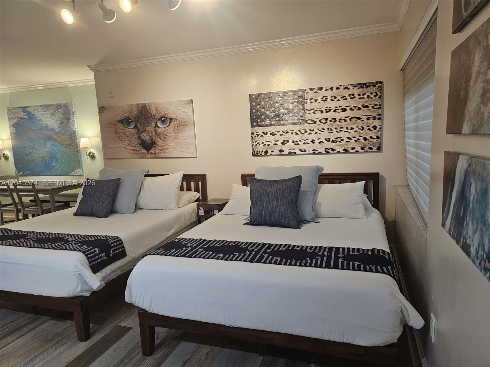 A bedroom features two beds with dark wood frames and unique wall art — 1024 Ocean Dr # A305, Miami Beach FL 33139, MIAMI BEACH, FL
