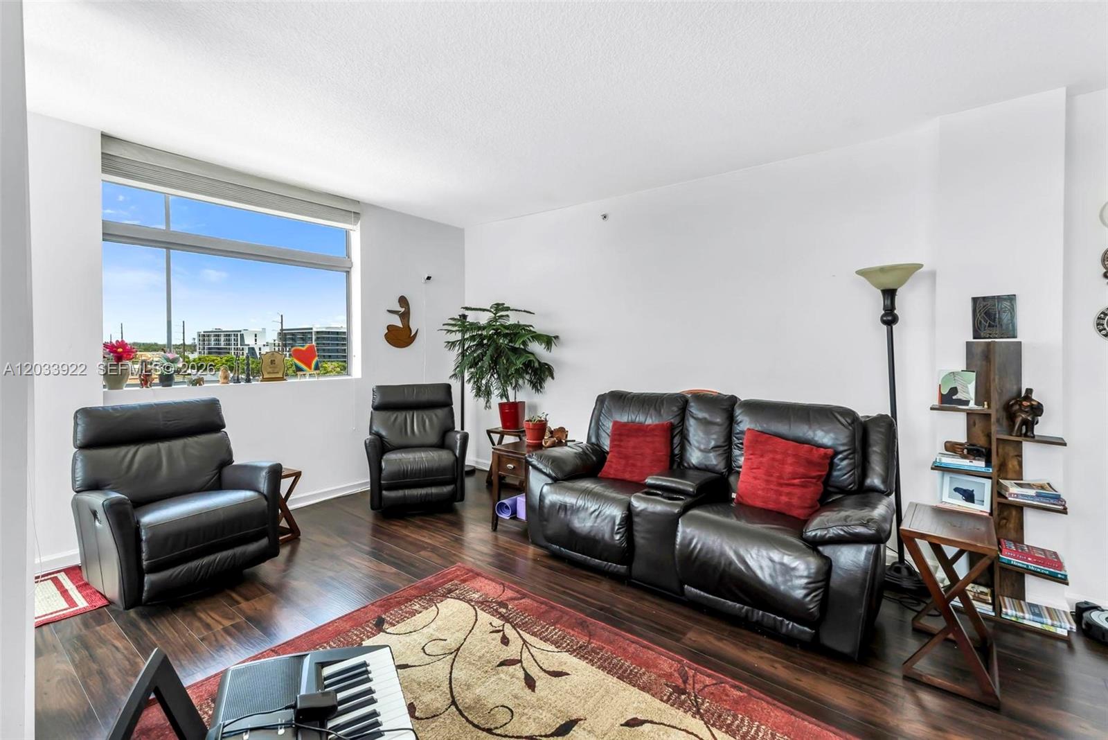 A living room features dark leather seating, a patterned rug, and a large window view — 140 S Dixie Hwy # 501, Hollywood FL 33020, HOLLYWOOD, FL