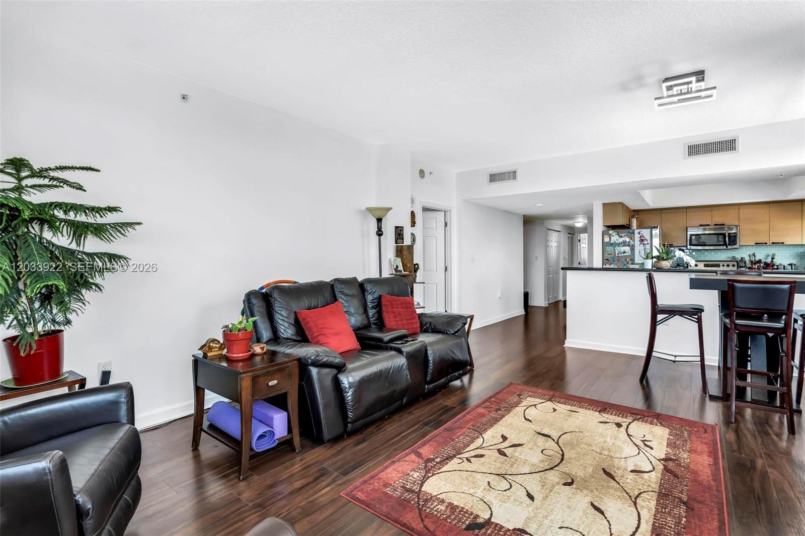 A living room with dark wood floors, a black leather sofa, and an open kitchen — 140 S Dixie Hwy # 501, Hollywood FL 33020, HOLLYWOOD, FL