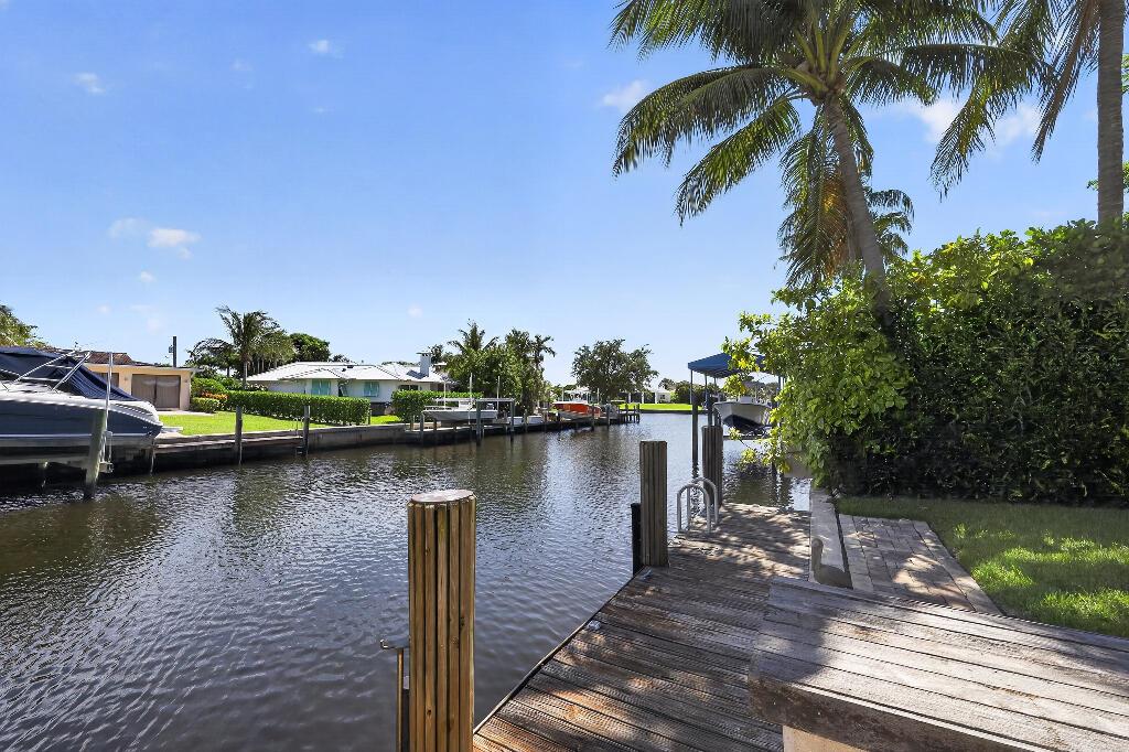 A wooden dock sits along a canal lined with palm trees and residential boat slips — 636 Kingfish Road, North Palm Beach FL 33408, NORTH PALM BEACH, FL