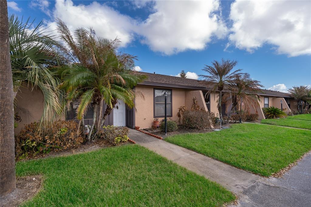 A single-story tan stucco townhouse with a palm tree and a concrete walkway — 2123 ST MARTEEN COURT, KISSIMMEE, FL