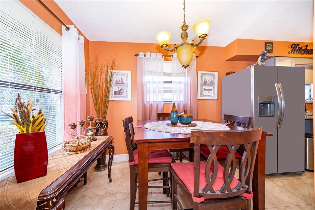 A dining room features orange walls, a wooden table with chairs, and a nearby refrigerator — 2123 ST MARTEEN COURT, KISSIMMEE, FL