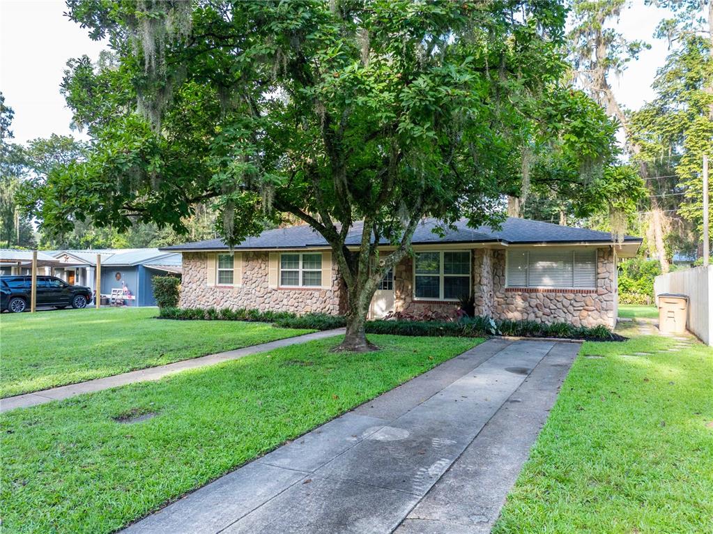 A single-story house with a stone facade and a large tree in the front yard — 1443 SE VALE COURT, LAKE CITY, FL