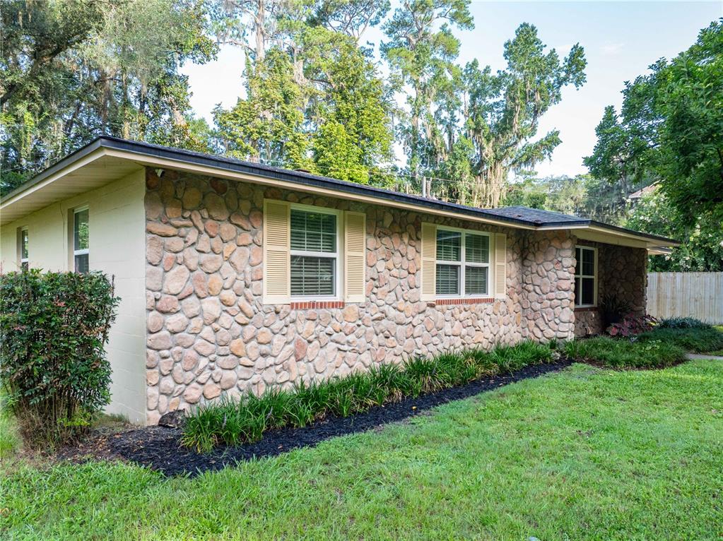 The exterior of a single-story house features stone veneer siding and beige shutters — 1443 SE VALE COURT, LAKE CITY, FL