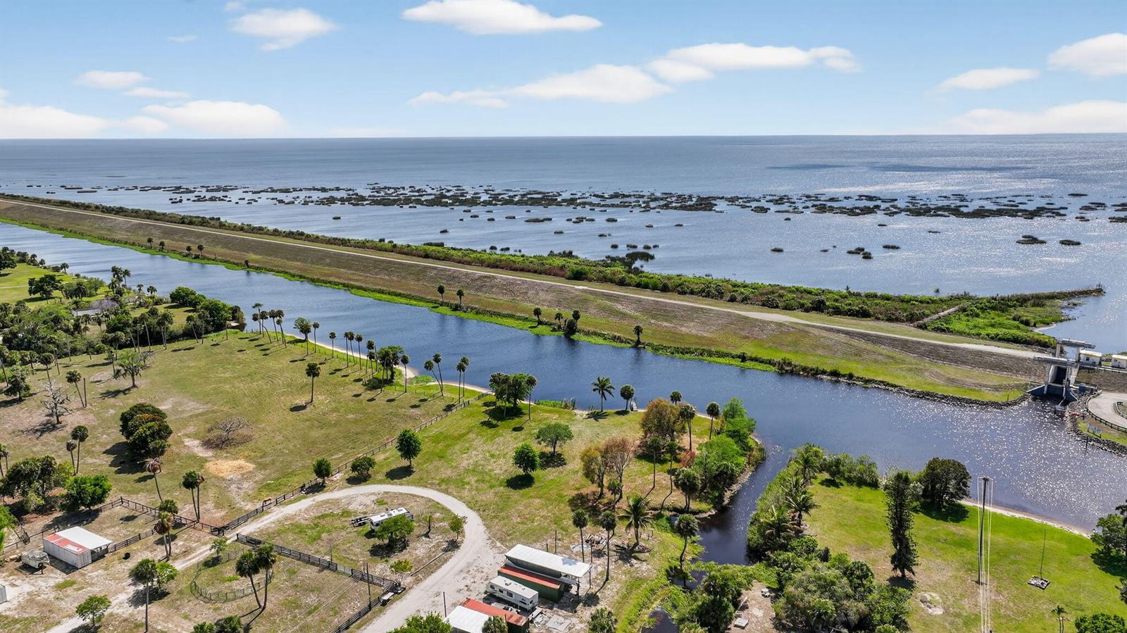 An aerial view shows a canal, a levee, and a large lake with scattered vegetation — 9700 SW Conners Highway, Okeechobee FL 34974, OKEECHOBEE, FL