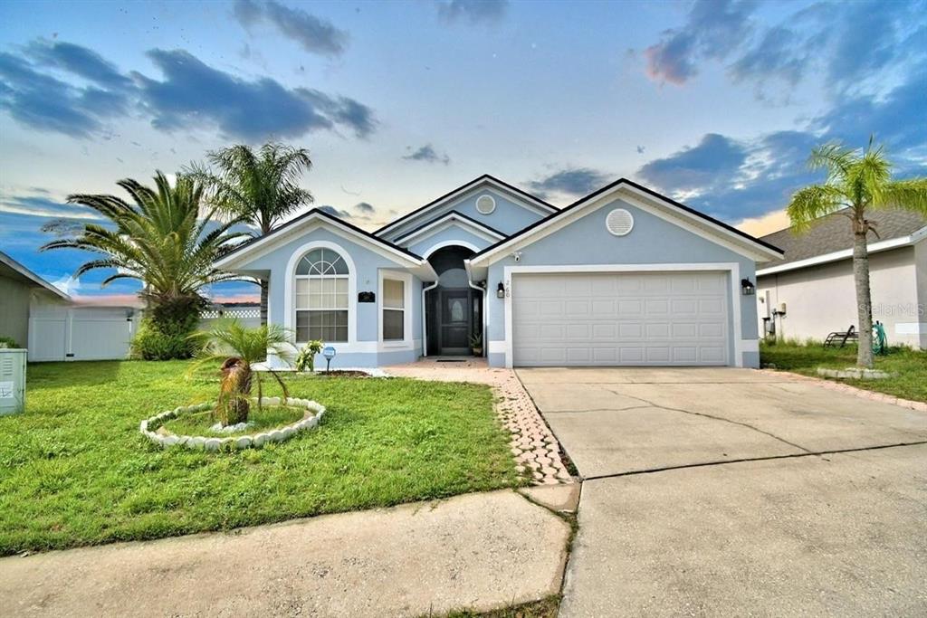 A single-story house with a light blue exterior, a two-car garage, and a palm tree — 260 CHESHIRE WAY, DAVENPORT, FL