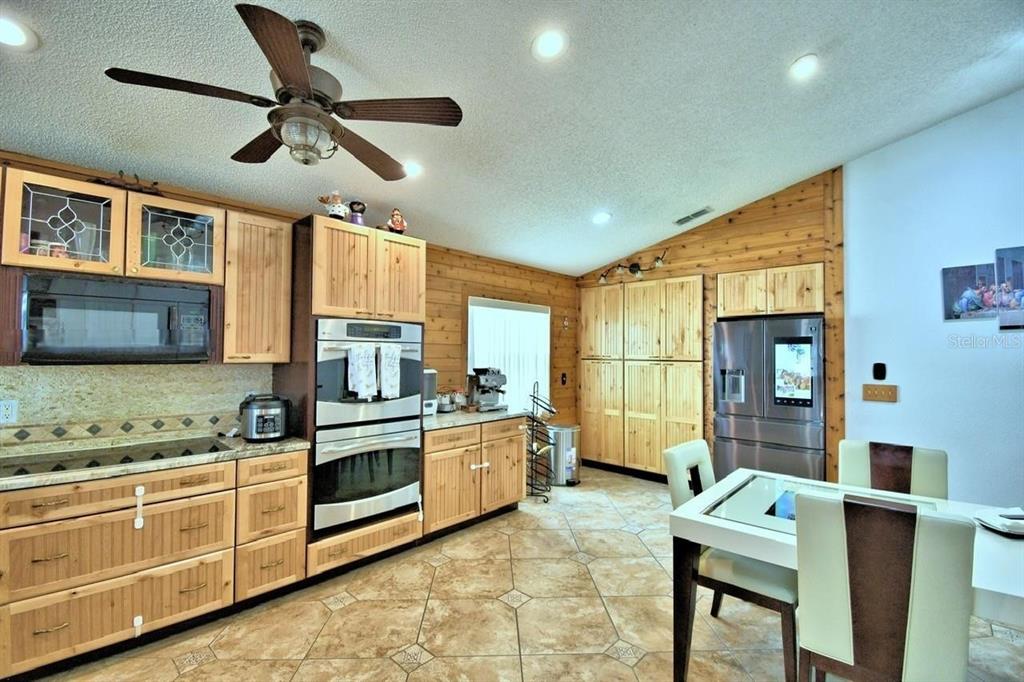 A kitchen features light wood cabinetry, stainless steel appliances, and tile flooring — 260 CHESHIRE WAY, DAVENPORT, FL