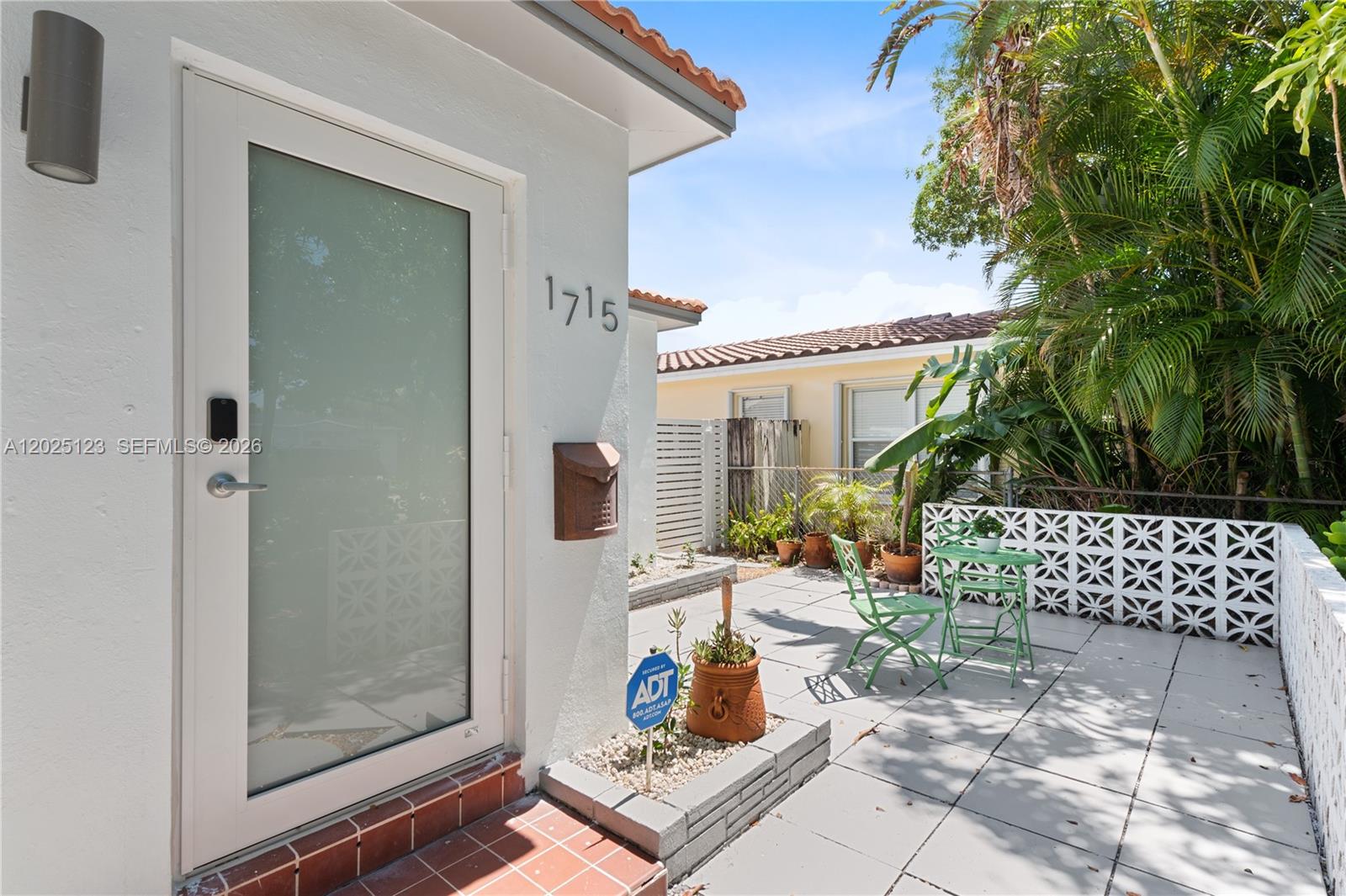 A white exterior wall with a glass door, house number, and a small paved patio area — 1715 Jefferson St # 0, Hollywood FL 33020, HOLLYWOOD, FL
