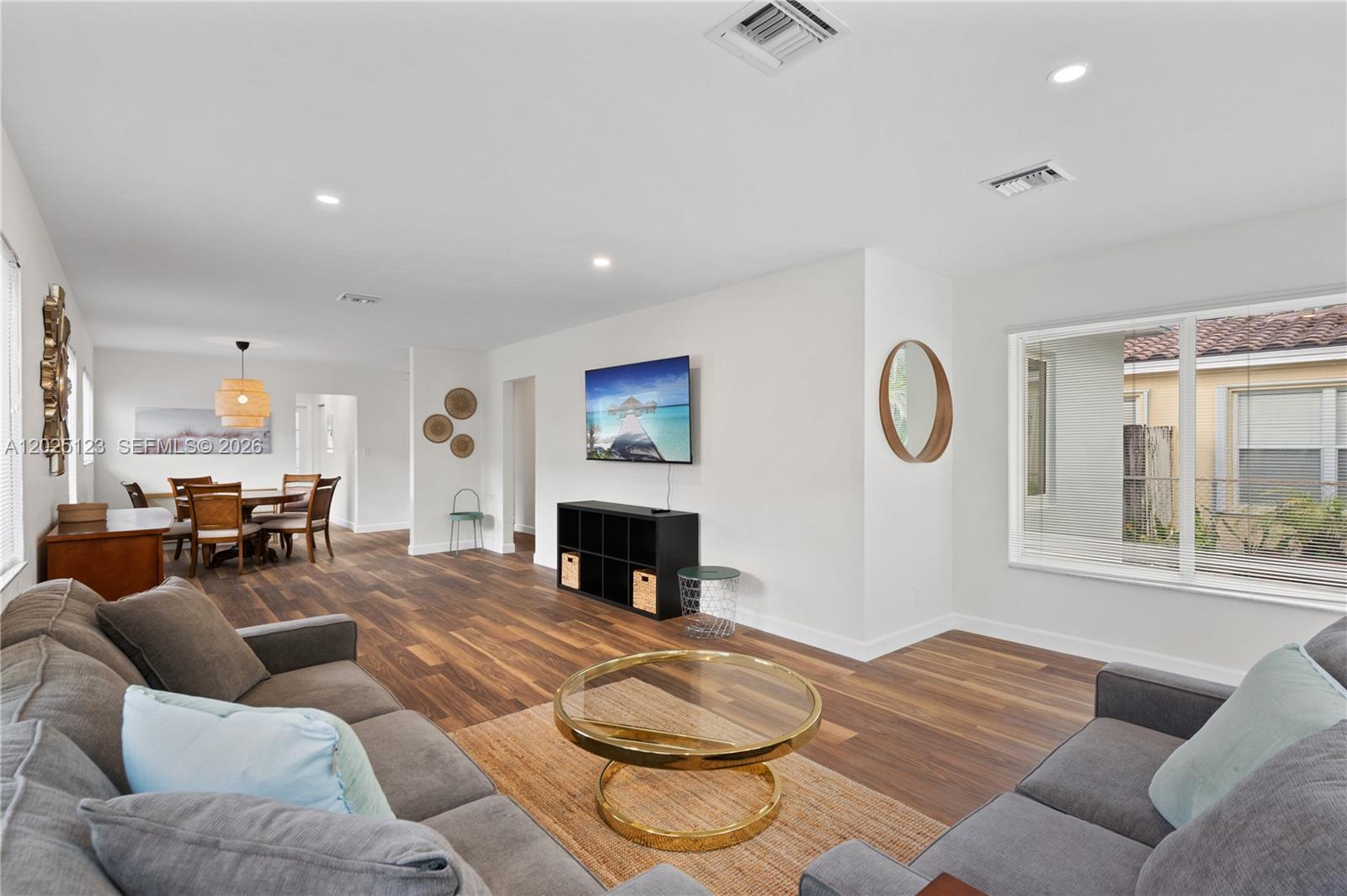 A living room with wood-look flooring, gray sofas, a glass coffee table, and a dining area — 1715 Jefferson St # 0, Hollywood FL 33020, HOLLYWOOD, FL