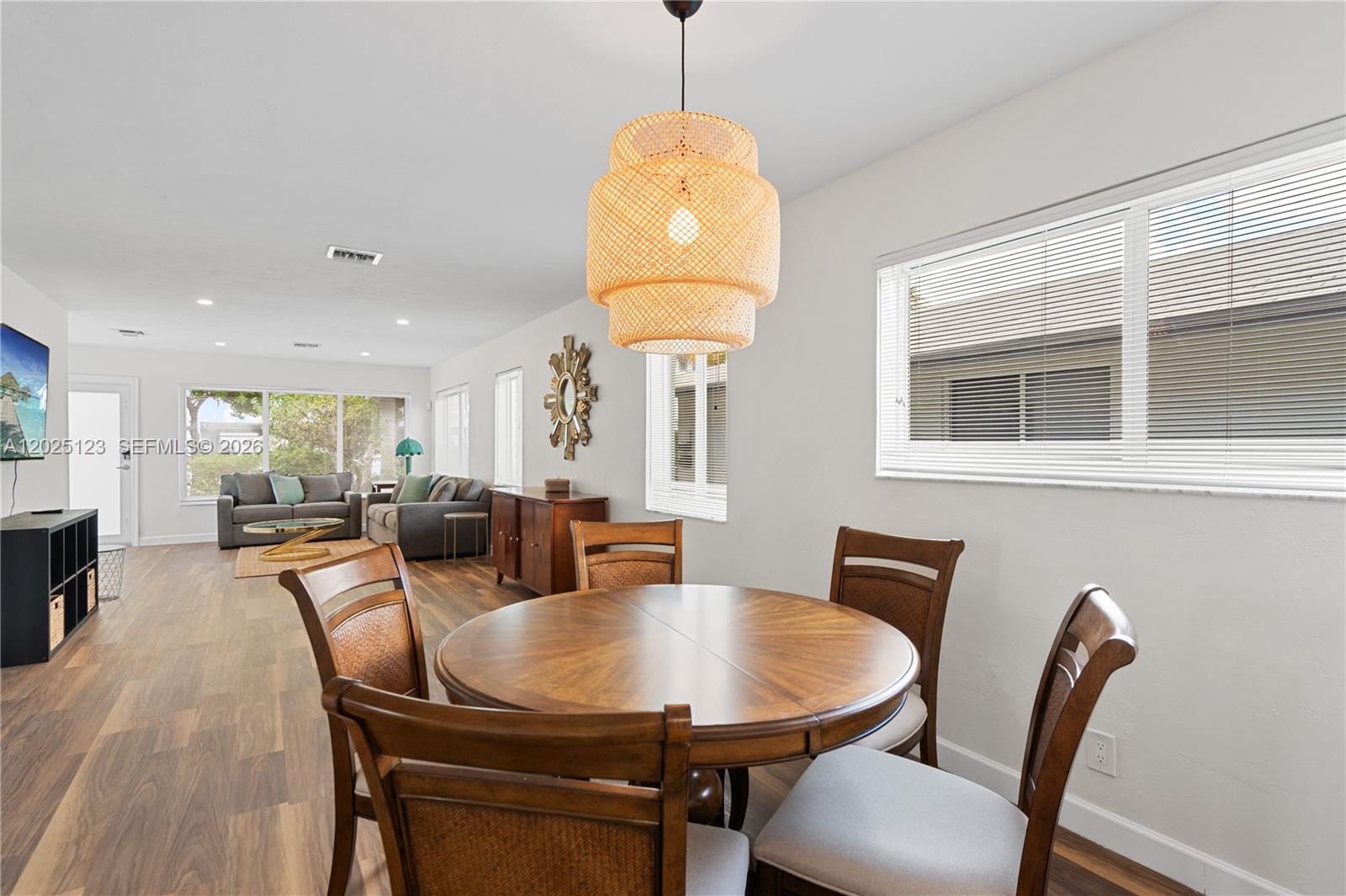 A dining area with a round wooden table and woven pendant light opens to a living room — 1715 Jefferson St # 0, Hollywood FL 33020, HOLLYWOOD, FL