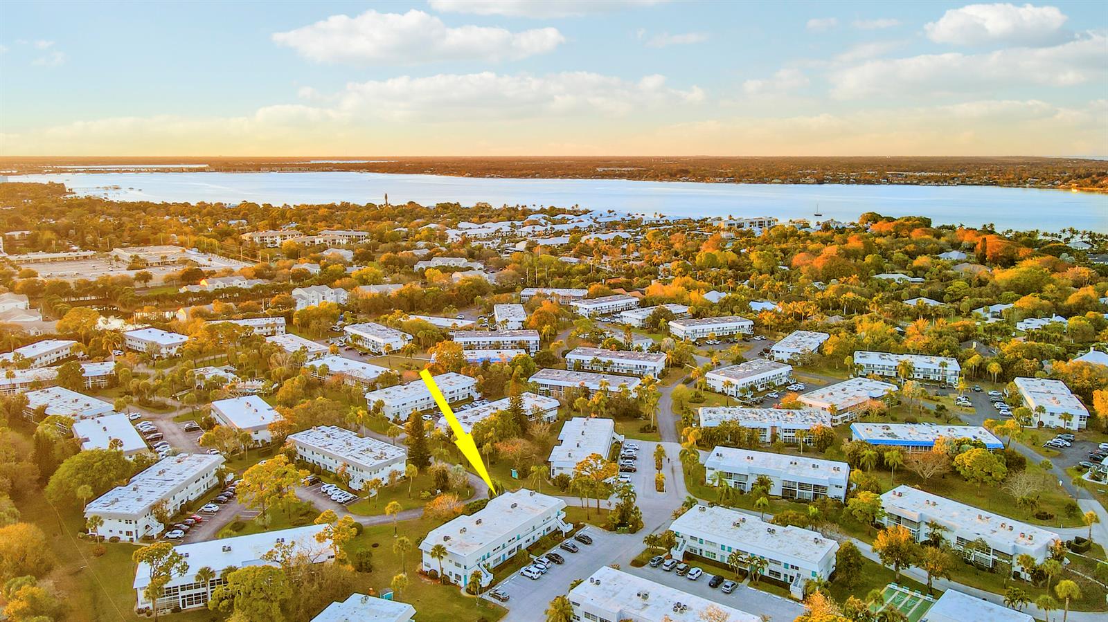 An aerial view shows a multi-story apartment complex surrounded by trees near a large body of water — 2929 SE Ocean Boulevard # 2, Stuart FL 34996, STUART, FL