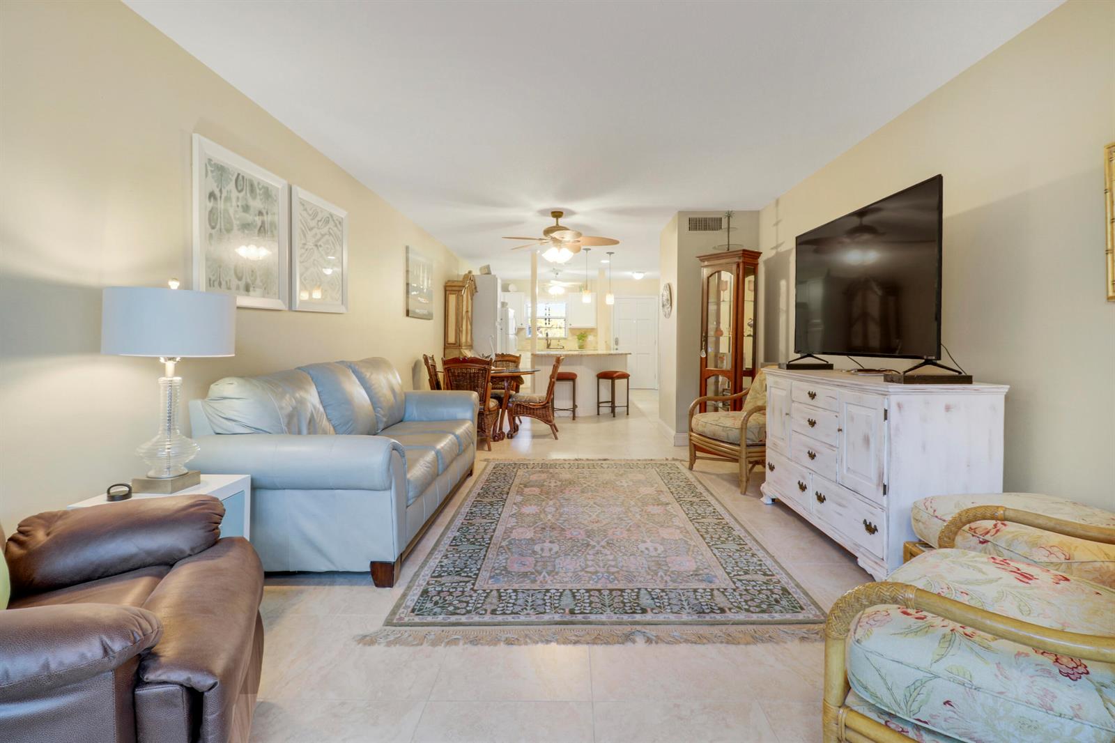 A living room features a light blue sofa, a patterned area rug, and a television console — 2929 SE Ocean Boulevard # 2, Stuart FL 34996, STUART, FL