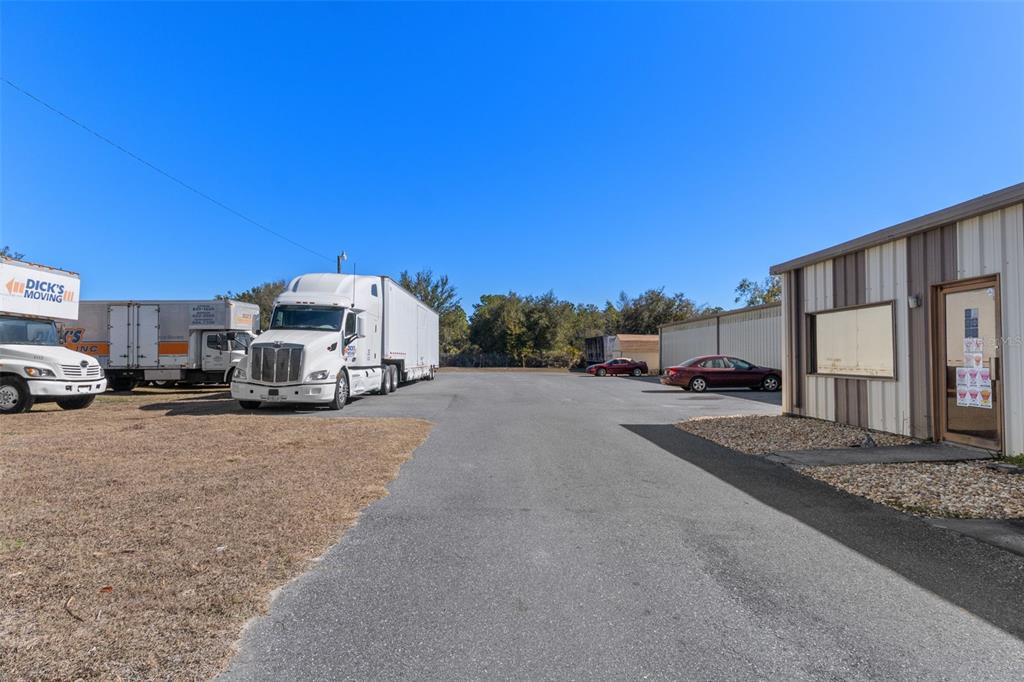 A paved lot features a parked semi-truck, a moving truck, and a metal commercial building — 6331 & 6275 S TEX POINT, HOMOSASSA, FL