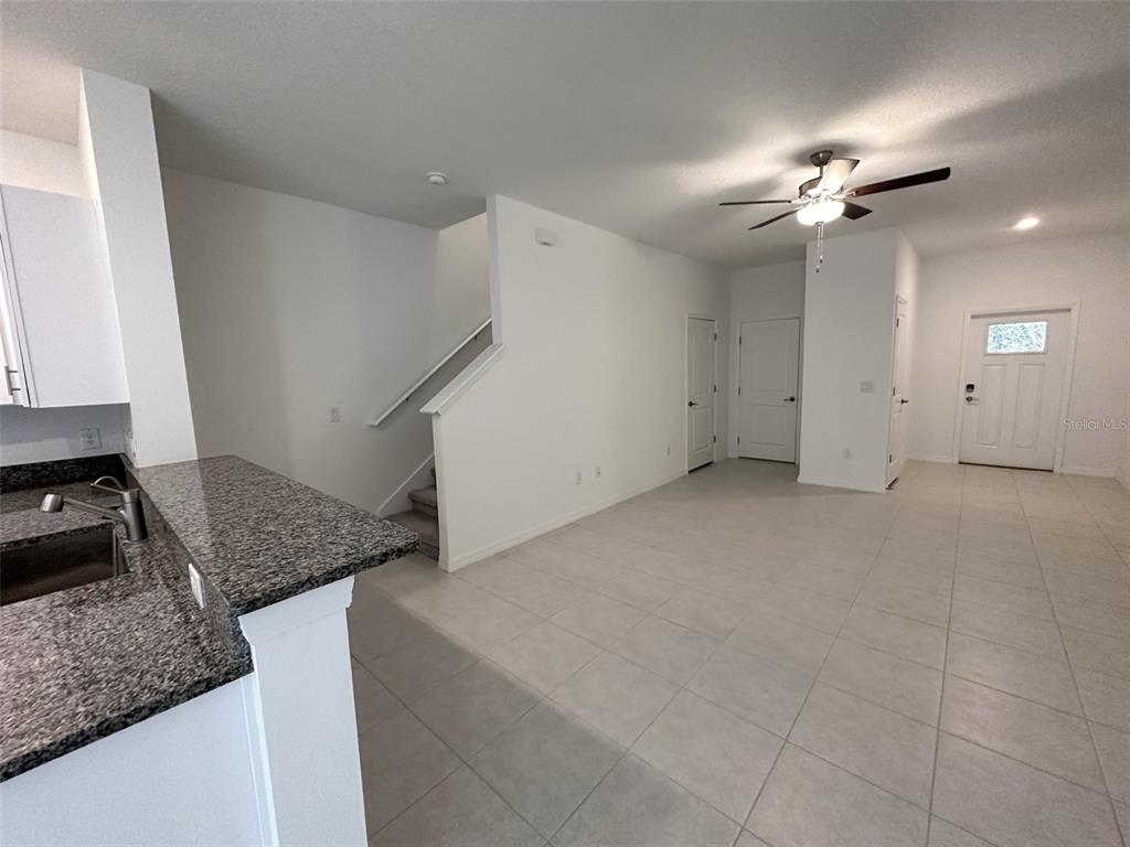 A kitchen counter overlooks an open-concept living area with tile flooring and a staircase — 17616 NECTAR FLUME DRIVE, LAND O LAKES, FL
