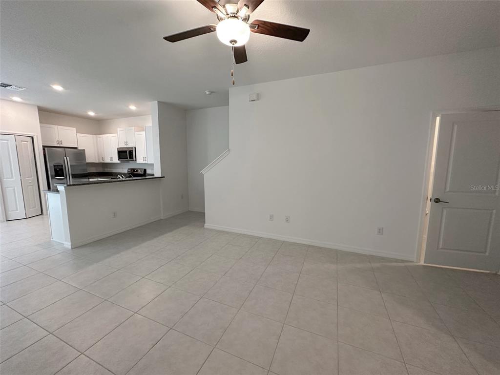 This interior view shows a tiled living area with a ceiling fan and open kitchen — 17616 NECTAR FLUME DRIVE, LAND O LAKES, FL