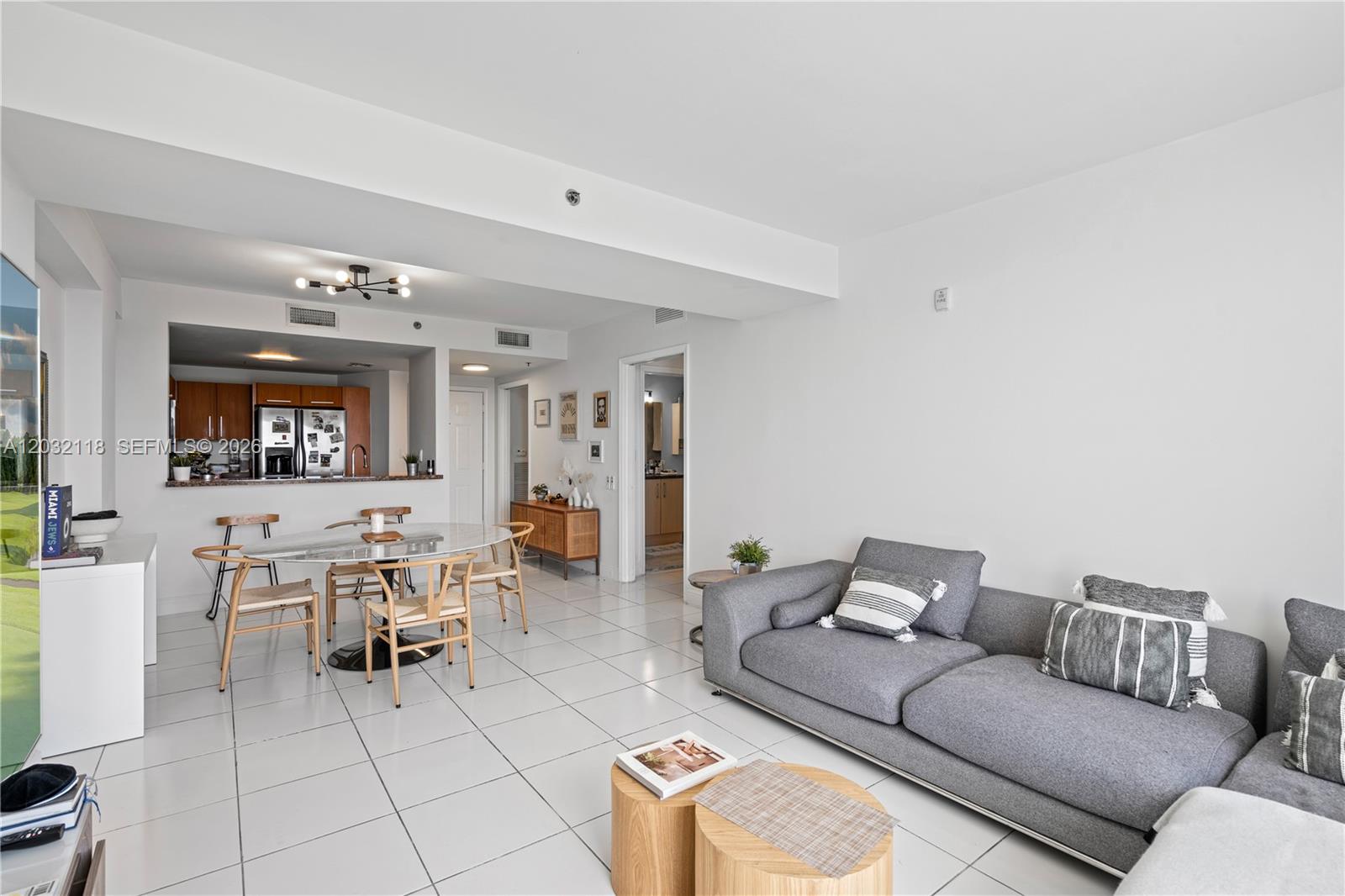 A living room and dining area feature white tile floors, a gray sofa, and kitchen — 6362 Collins Ave # 312, Miami Beach FL 33141, MIAMI BEACH, FL