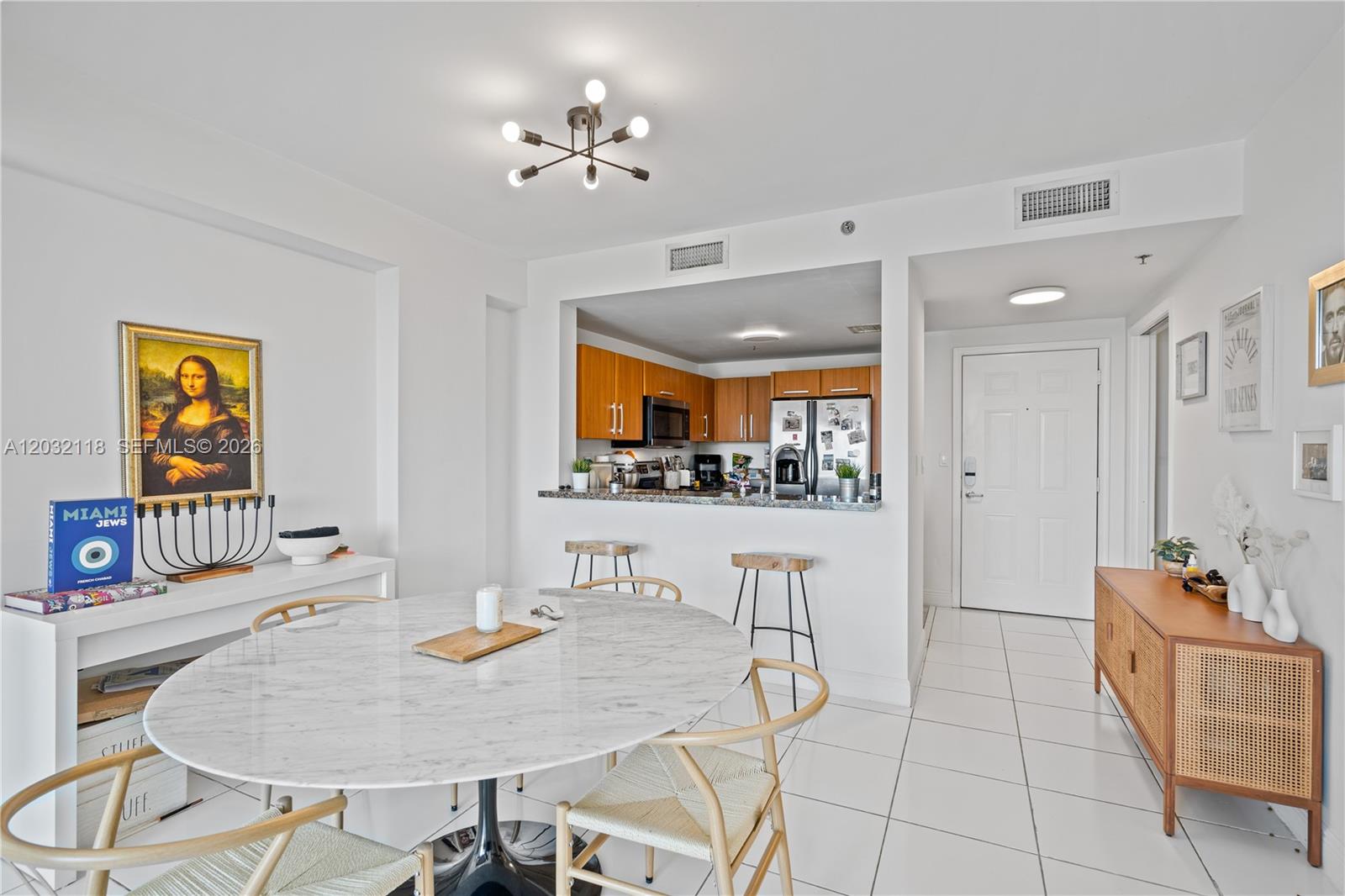 A dining area with a marble table and chairs sits adjacent to an open kitchen — 6362 Collins Ave # 312, Miami Beach FL 33141, MIAMI BEACH, FL