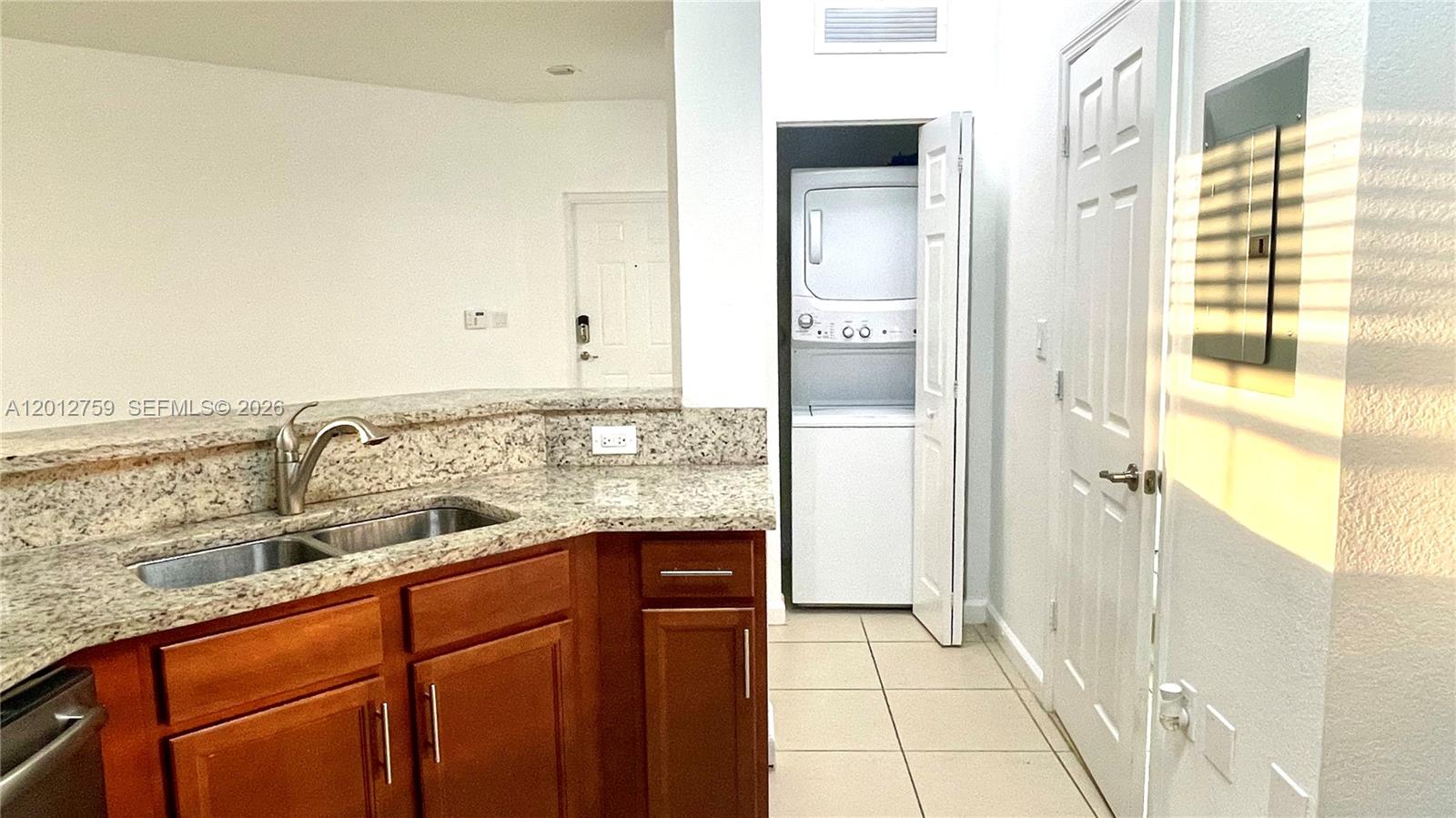 A kitchen with granite countertops and a sink overlooks a laundry closet with stacked appliances — 10620 NW 88th St # 205, Doral FL 33178, DORAL, FL