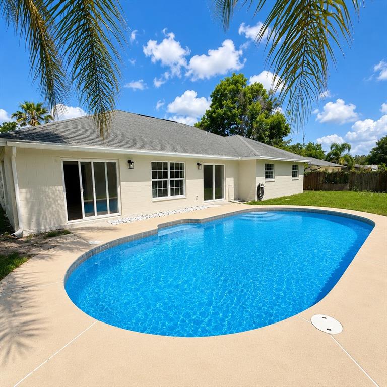A beige house with a shingled roof features a backyard swimming pool and patio — 641 BROOKSIDE ROAD, MAITLAND, FL