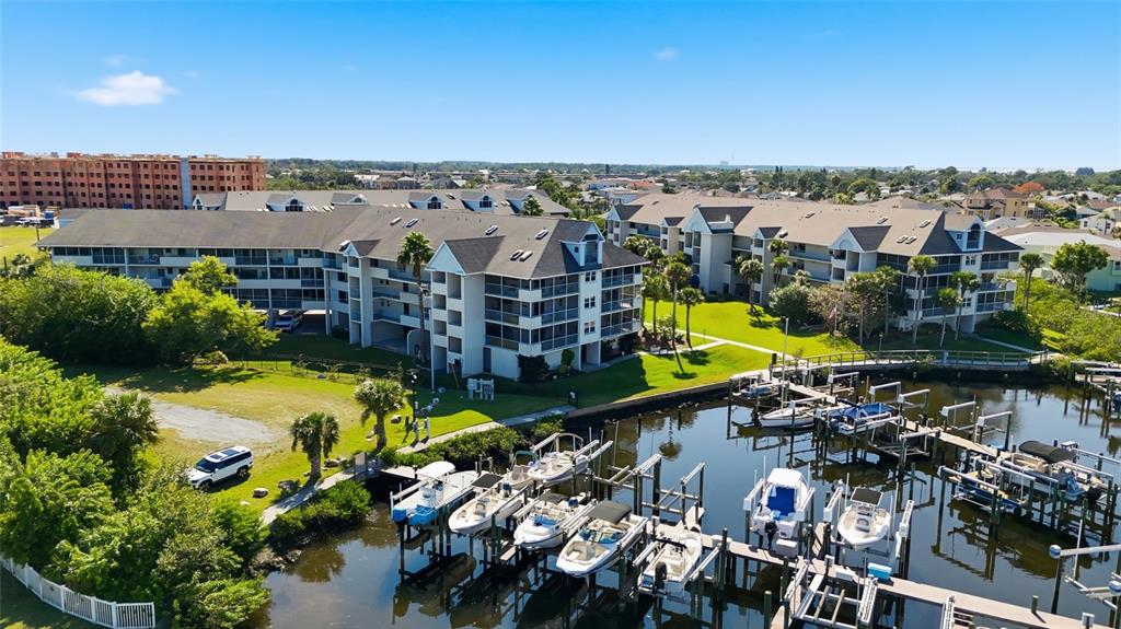 An aerial view shows multi-story apartment buildings next to a marina with docked boats — 5567 SEA FOREST DRIVE UNIT 323, NEW PORT RICHEY, FL