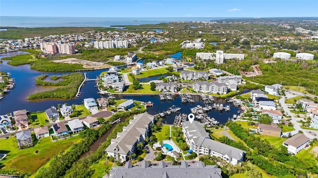 An aerial view shows a waterfront residential complex with boat slips and a swimming pool — 5567 SEA FOREST DRIVE UNIT 323, NEW PORT RICHEY, FL