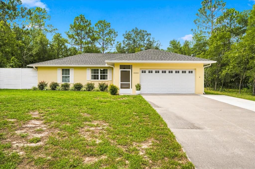 A yellow single-story house with a white garage door and a concrete driveway — 3032 E PORTER STREET UNIT 34, INVERNESS, FL