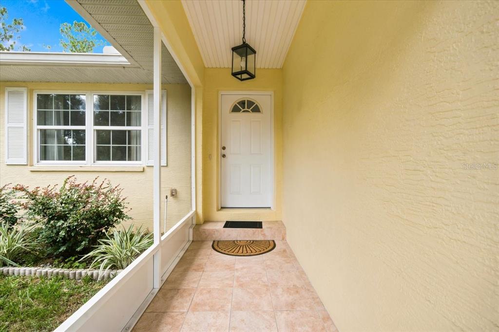 A covered entryway features a white front door, tiled floor, and a hanging lantern light — 3032 E PORTER STREET UNIT 34, INVERNESS, FL