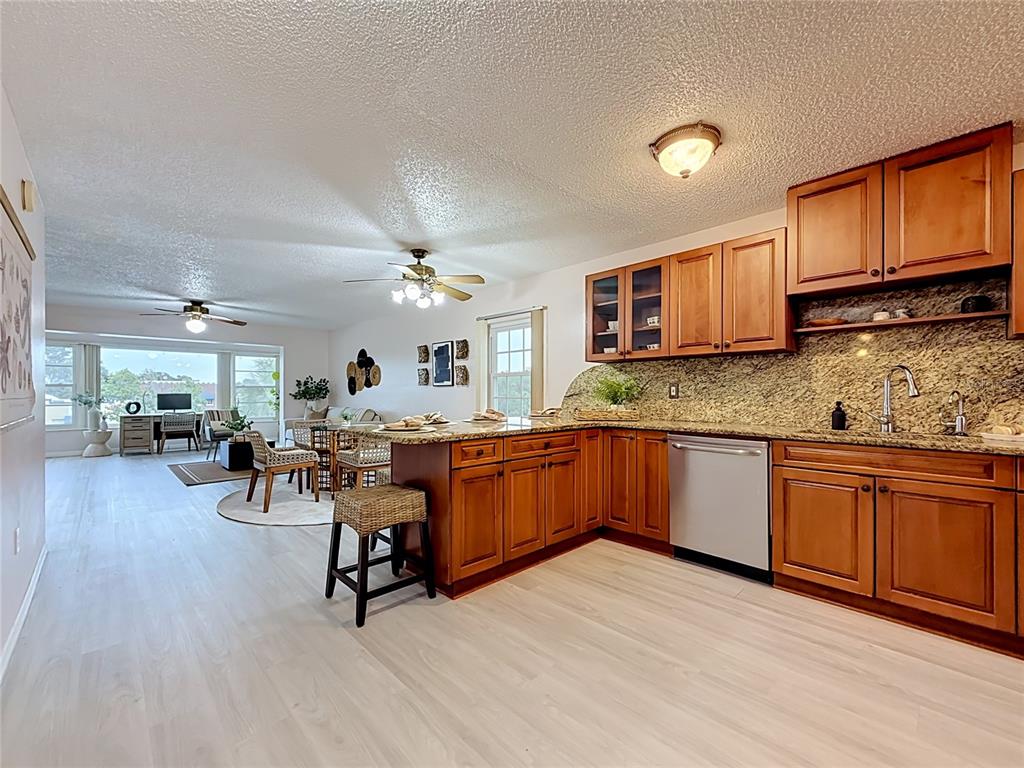 An open-concept kitchen with wood cabinets and granite countertops flows into a living area — 1900 68TH STREET N UNIT 301, ST PETERSBURG, FL
