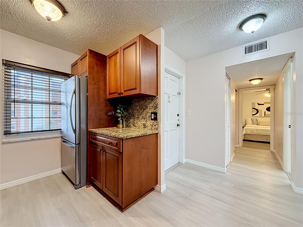 A kitchen area with wood cabinets, granite countertops, and a stainless steel refrigerator — 1900 68TH STREET N UNIT 301, ST PETERSBURG, FL
