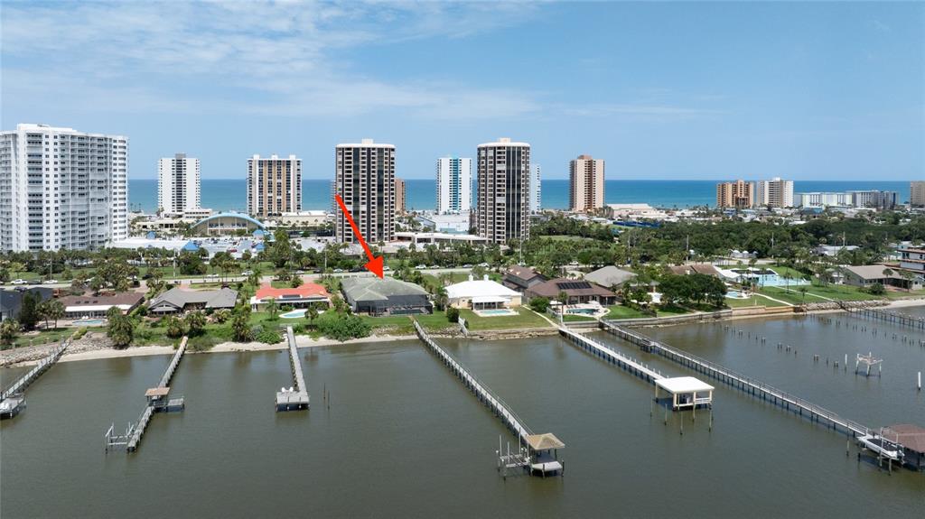 An aerial view shows a waterfront house with a pool and dock on the bay — 3020 S PENINSULA DRIVE, DAYTONA BEACH SHORES, FL