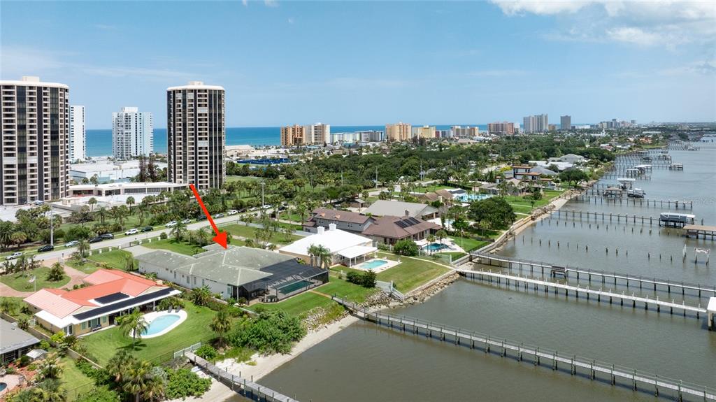 An aerial view shows a waterfront house with a pool and dock on the coast — 3020 S PENINSULA DRIVE, DAYTONA BEACH SHORES, FL