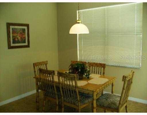 A dining room features a bamboo-style table and chairs beneath a pendant light near a window — 622 ALFANI STREET, DAVENPORT, FL