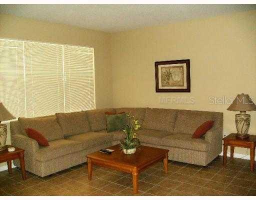 A living room features a large beige sectional sofa, a wooden coffee table, and tile flooring — 622 ALFANI STREET, DAVENPORT, FL