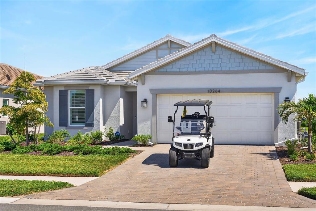 A white single-story house with a paved driveway and a golf cart parked in front — 10264 BEACH DUNE DRIVE, ENGLEWOOD, FL