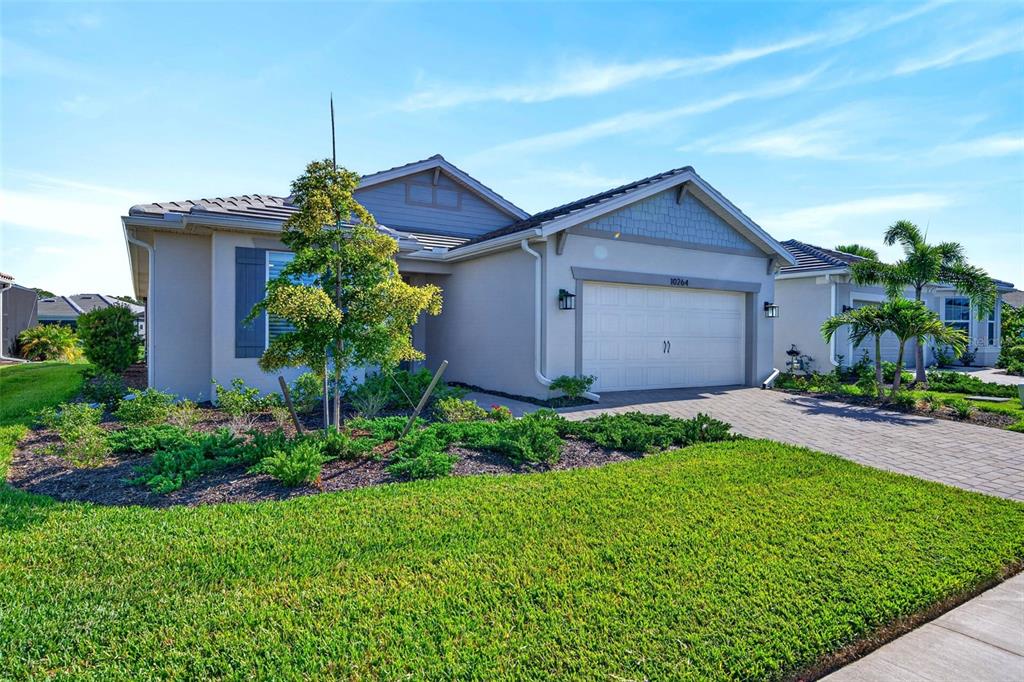 A single-story house with a two-car garage, light-colored siding, and a landscaped front yard — 10264 BEACH DUNE DRIVE, ENGLEWOOD, FL
