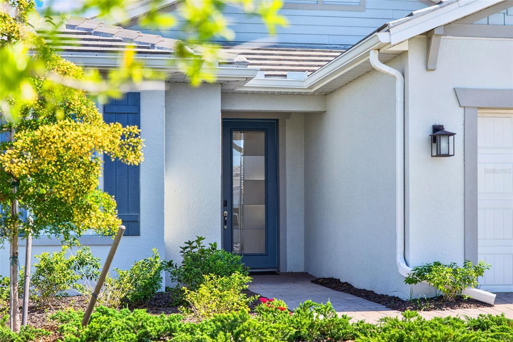 A blue front door with glass panels is centered on the light-colored house exterior — 10264 BEACH DUNE DRIVE, ENGLEWOOD, FL