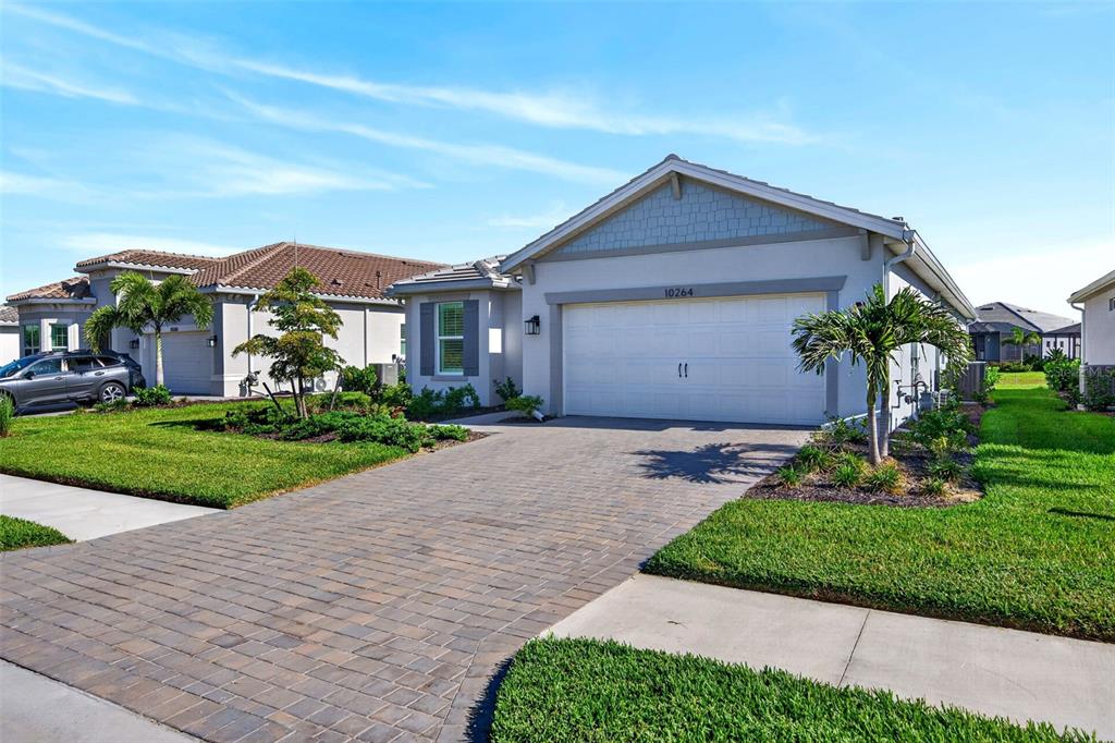 A single-story house with a white garage, paved driveway, and palm trees in the front yard — 10264 BEACH DUNE DRIVE, ENGLEWOOD, FL