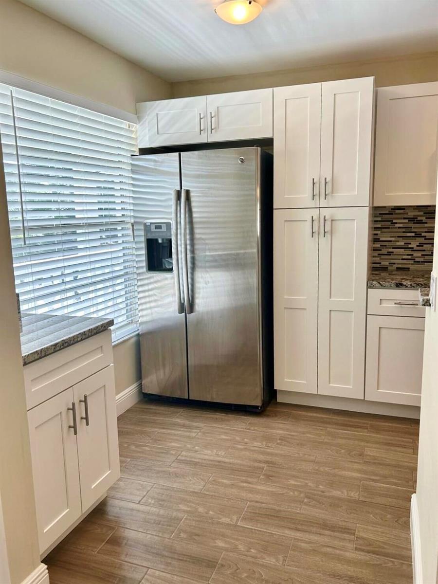 A kitchen features white cabinets, a stainless steel refrigerator, and wood-look tile flooring — 2811 SW 15th Street # 202, Delray Beach FL 33445, DELRAY BEACH, FL