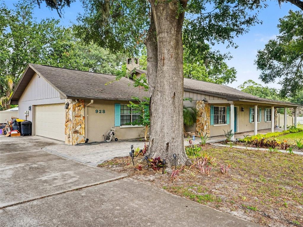 A single-story house with a stone-accented facade, a large tree, and a concrete driveway — 928 TIMBERGREEN DRIVE, LAKELAND, FL