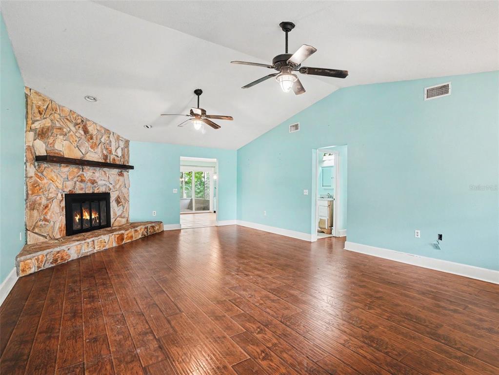 A living room features light blue walls, a stone fireplace, and dark wood-look flooring — 928 TIMBERGREEN DRIVE, LAKELAND, FL