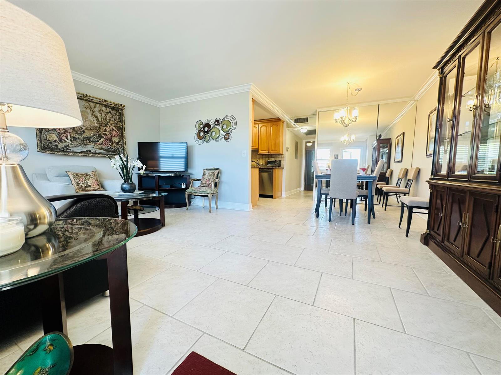 An open-concept living and dining area features light tile flooring and a mirrored wall — 310 Grantham A # 310, Deerfield Beach FL 33442, DEERFIELD BEACH, FL