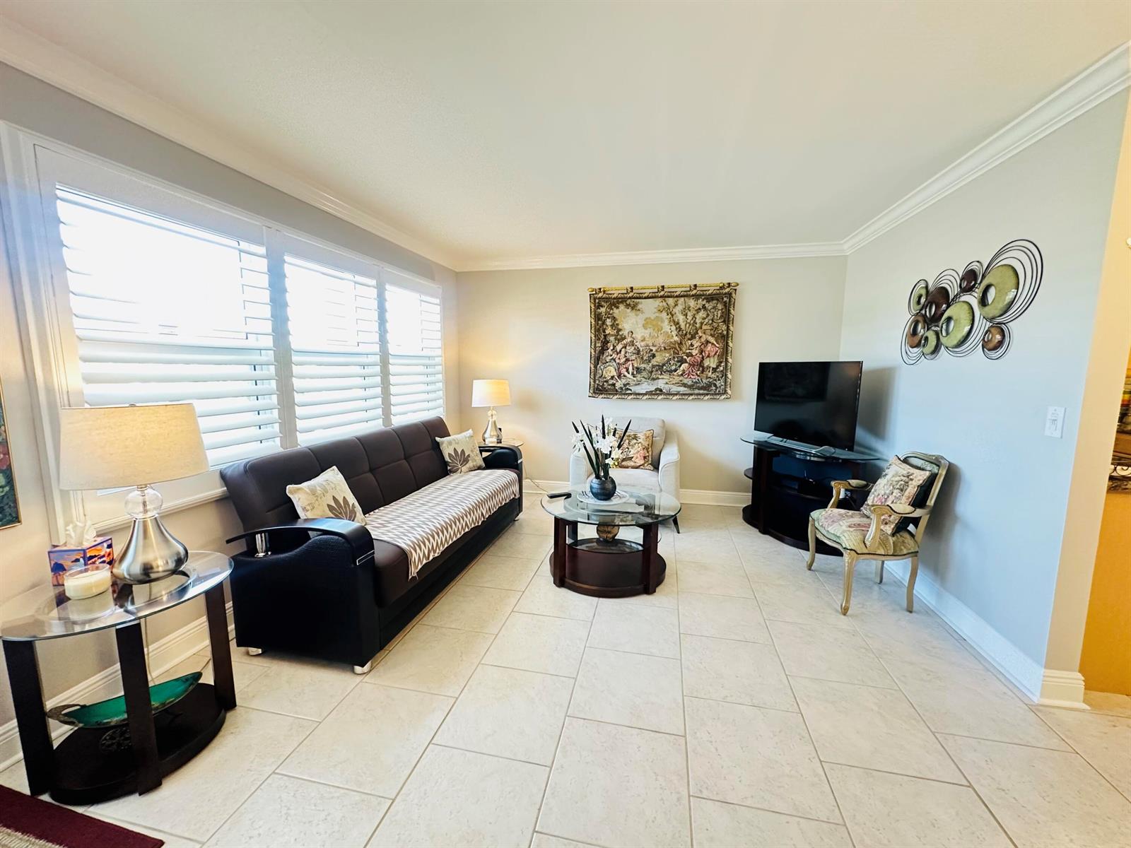 A living room features a dark sofa, a glass coffee table, and tile flooring — 310 Grantham A # 310, Deerfield Beach FL 33442, DEERFIELD BEACH, FL