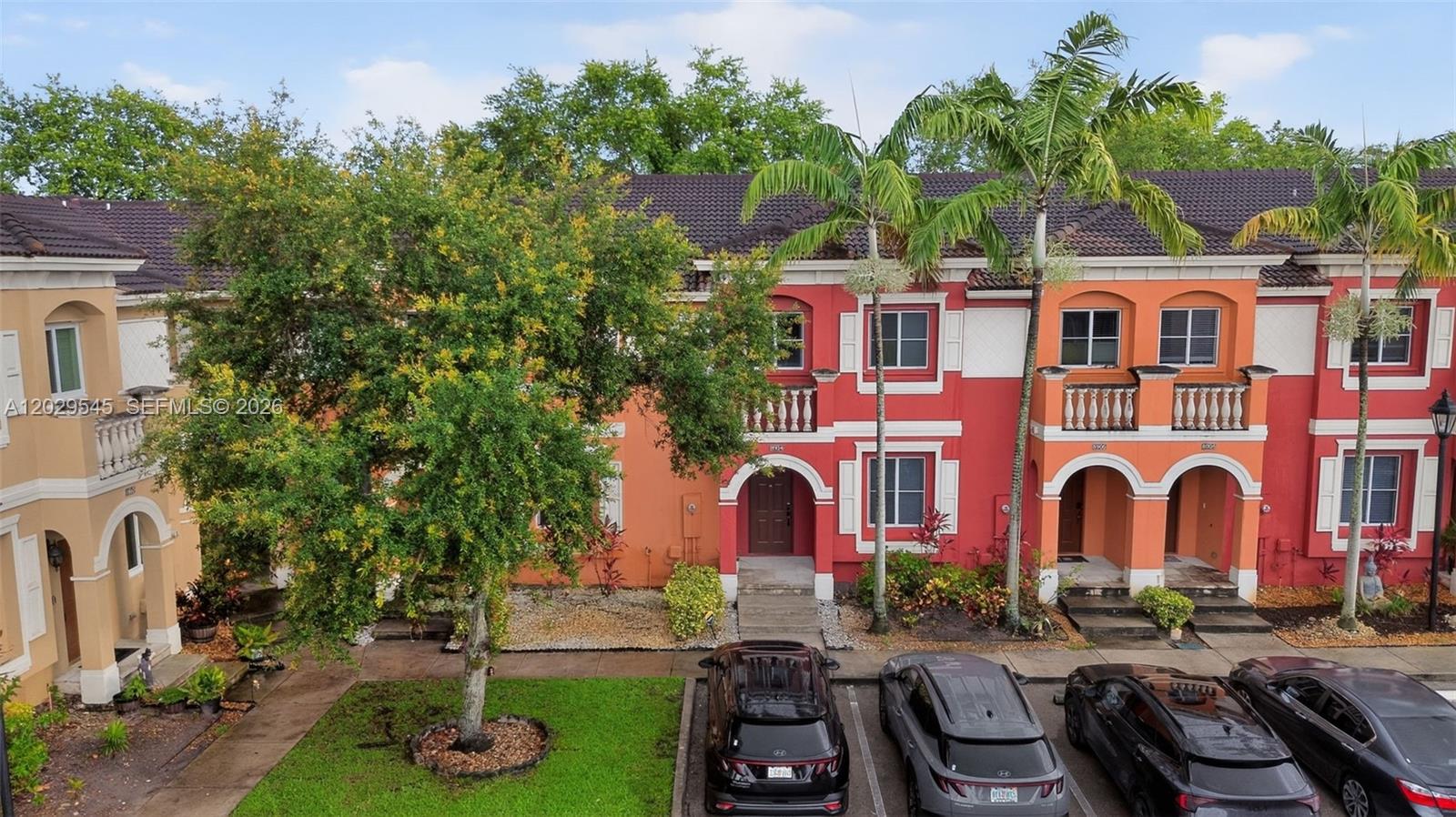 An exterior view of a multi-story townhouse complex with colorful facades and parked cars — 8904 SW 19th St, Miramar FL 33025, MIRAMAR, FL