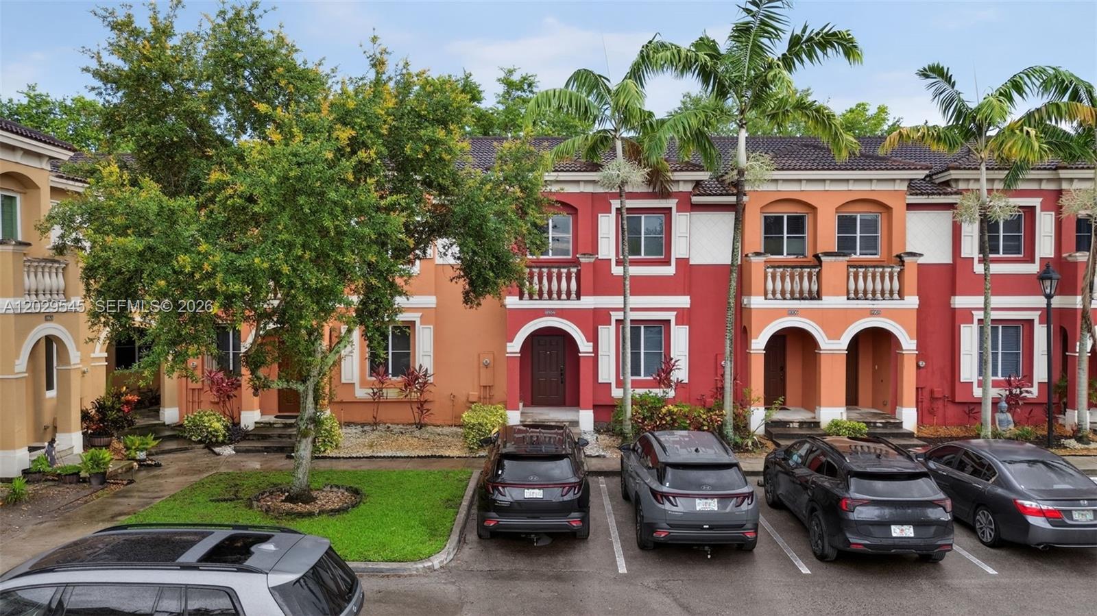 An exterior view of a row of colorful townhouses with parking spaces in front — 8904 SW 19th St, Miramar FL 33025, MIRAMAR, FL