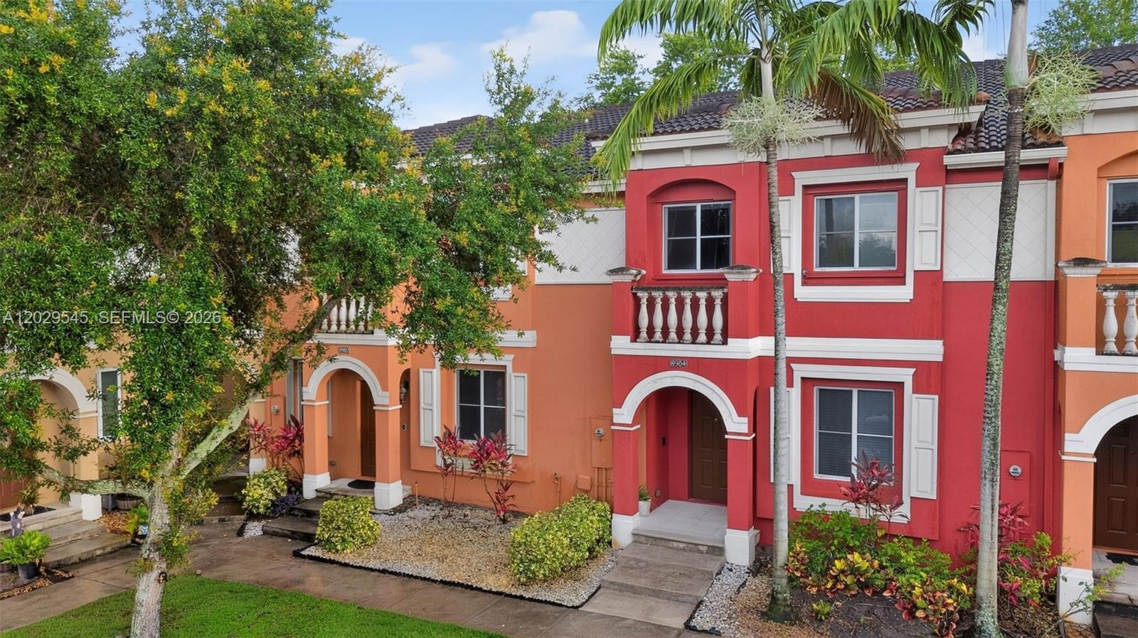 An exterior view of two adjacent multi-story townhomes with red and orange stucco facades — 8904 SW 19th St, Miramar FL 33025, MIRAMAR, FL