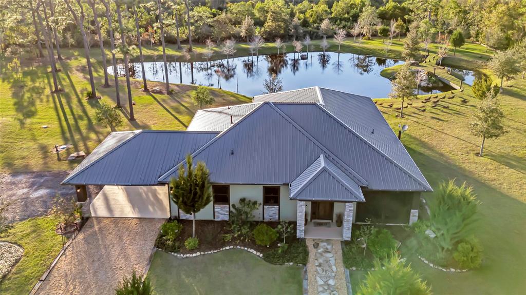 An aerial view shows a house with a metal roof, carport, and a backyard pond — 7330 CRABGRASS ROAD, ST CLOUD, FL