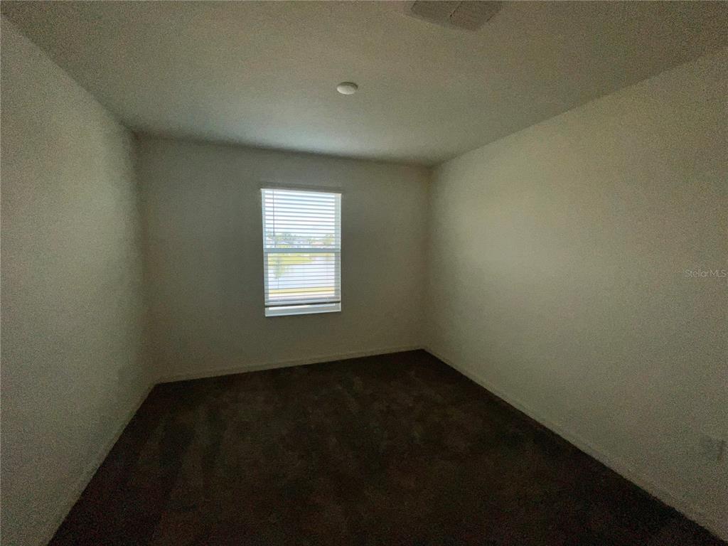 An empty bedroom features beige walls, dark brown carpeting, and a single window with blinds — 3805 HAMPTON CHASE LANE, SANFORD, FL